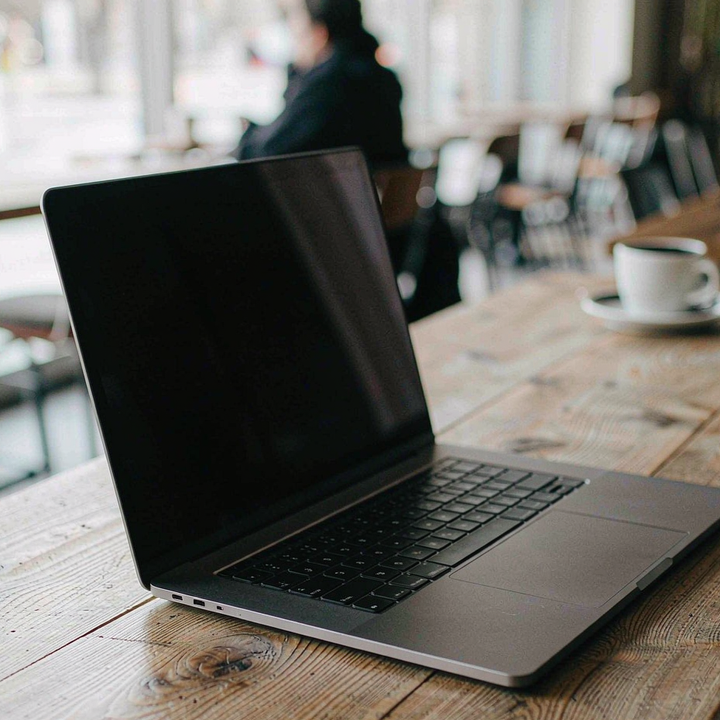 MacBook magnetic privacy screen in a coffee shop, the screen dark from a side angle